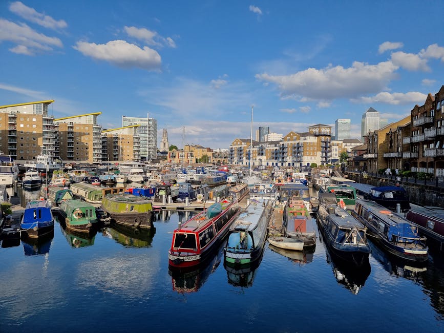 A photograph of a waterfront residential area in Limehouse featuring modern multi-storey buildings with large glass windows and balconies, situated along the riverbank. The buildings display a mix of 